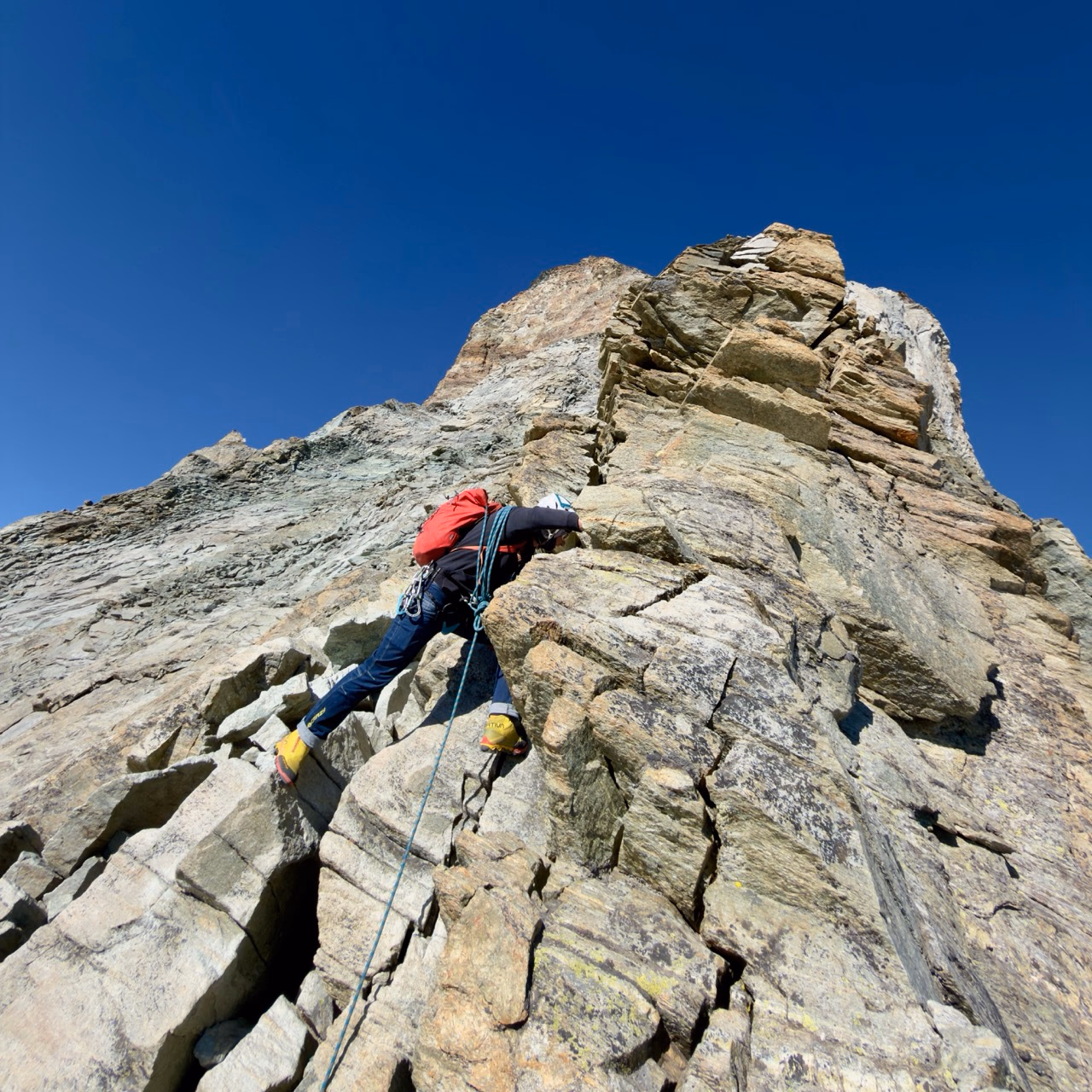 Downclimbing the steep, sunlit rock of the Hörnli Ridge.